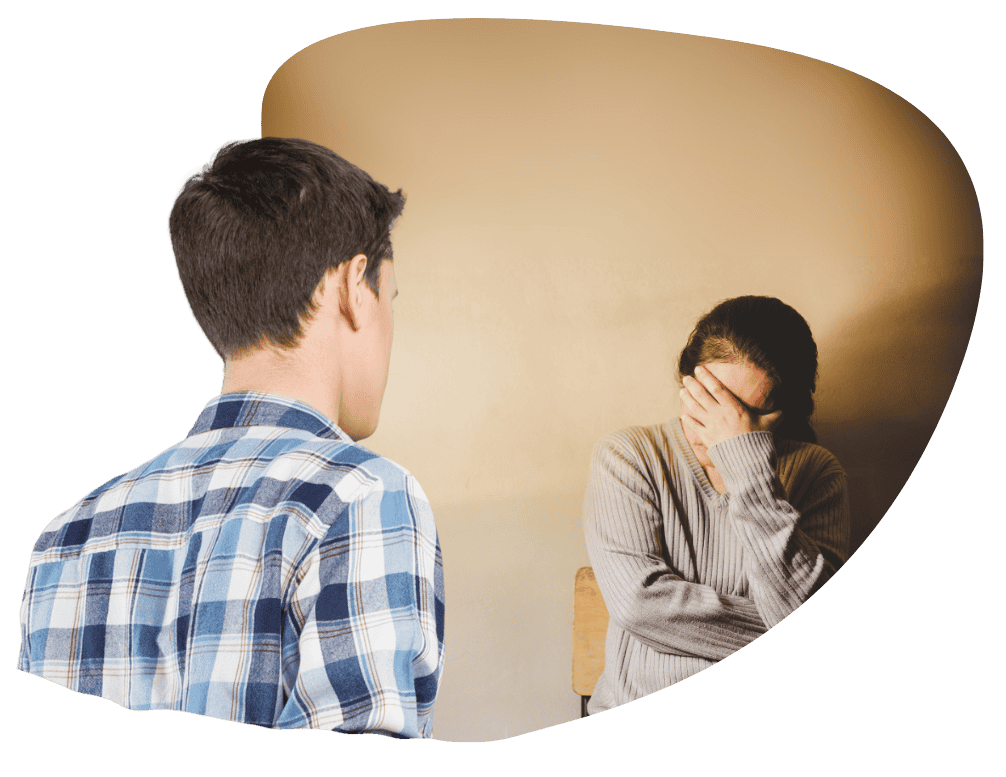 Behind the shoulder of a young man as he listens to a woman grieve 