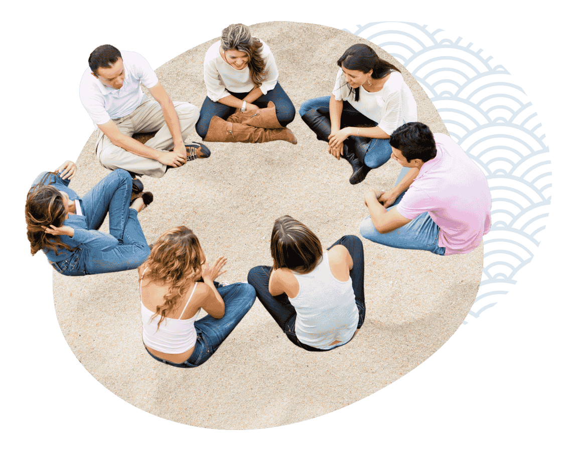A group people sitting in a circle on the sand